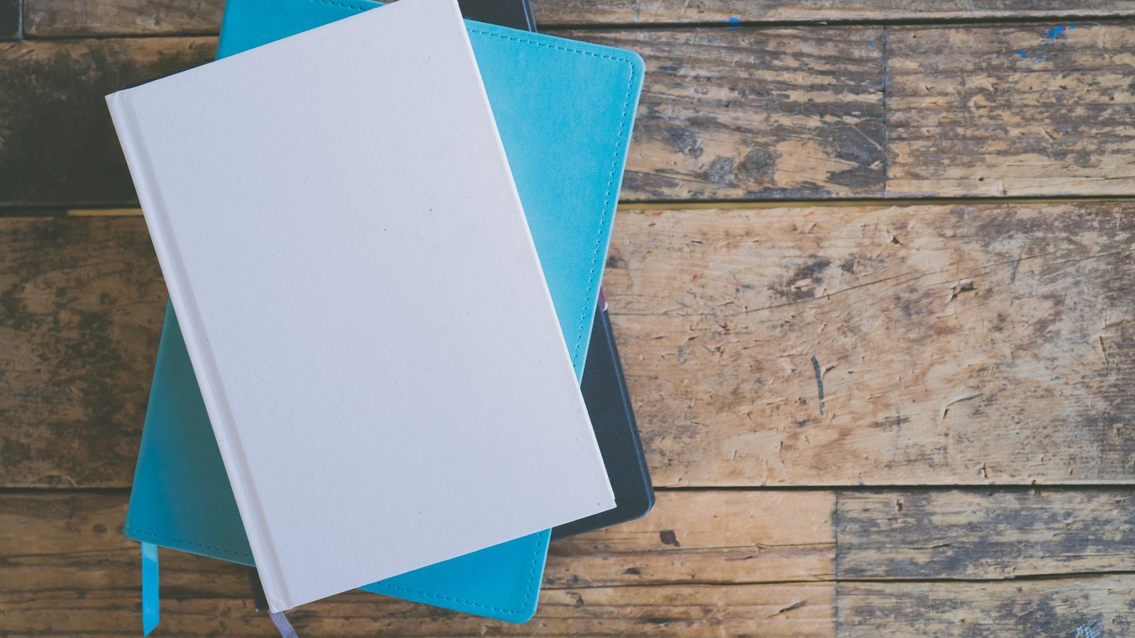 Une pile de livres et de carnets posée sur un bureau en bois